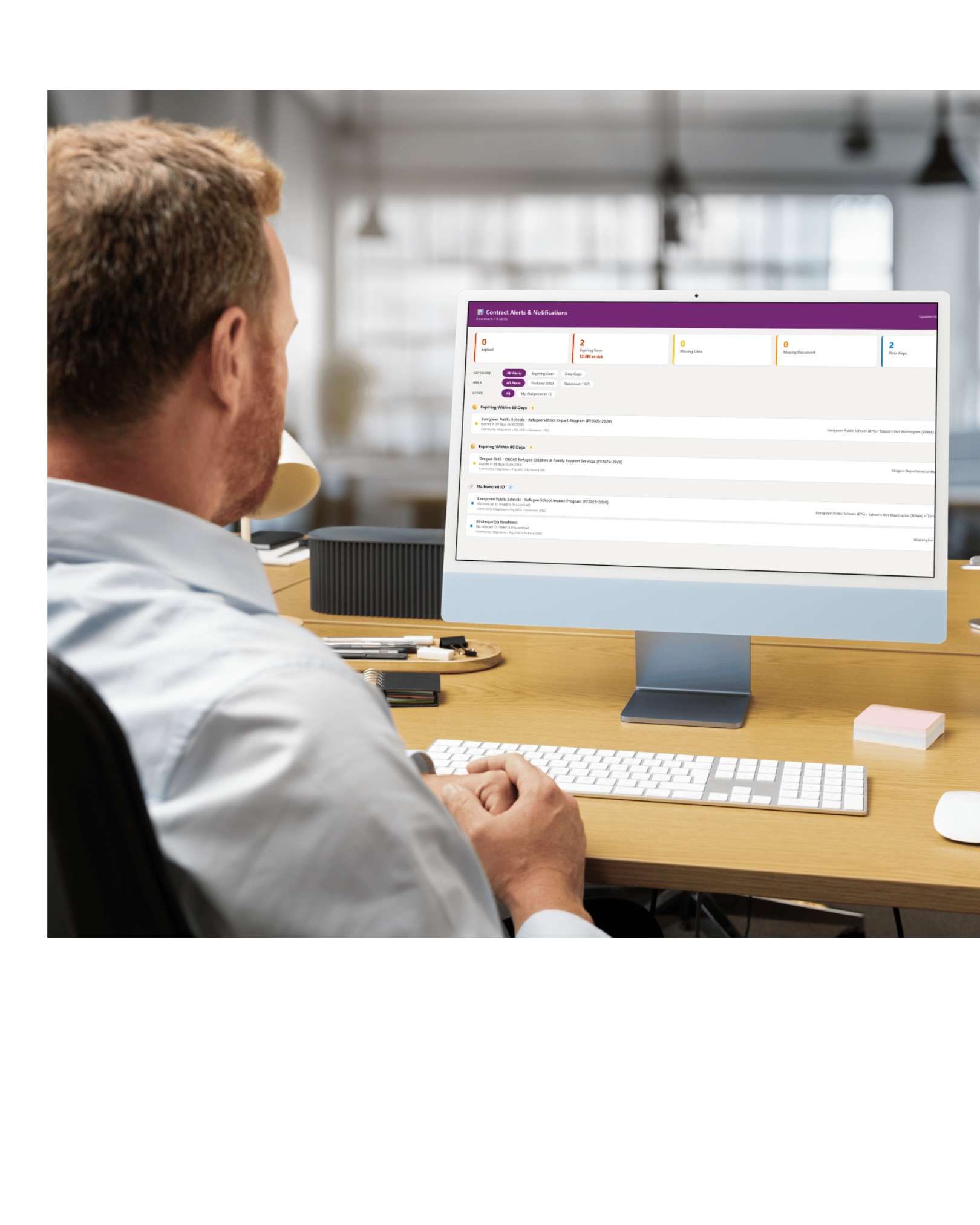 A person reviewing contract information on a desktop monitor, from the presentation